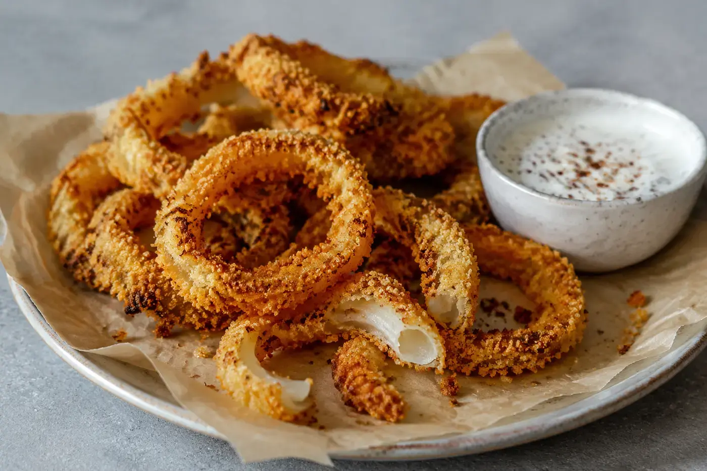 Zelfgemaakte krokante uienringen met yoghurtdip.